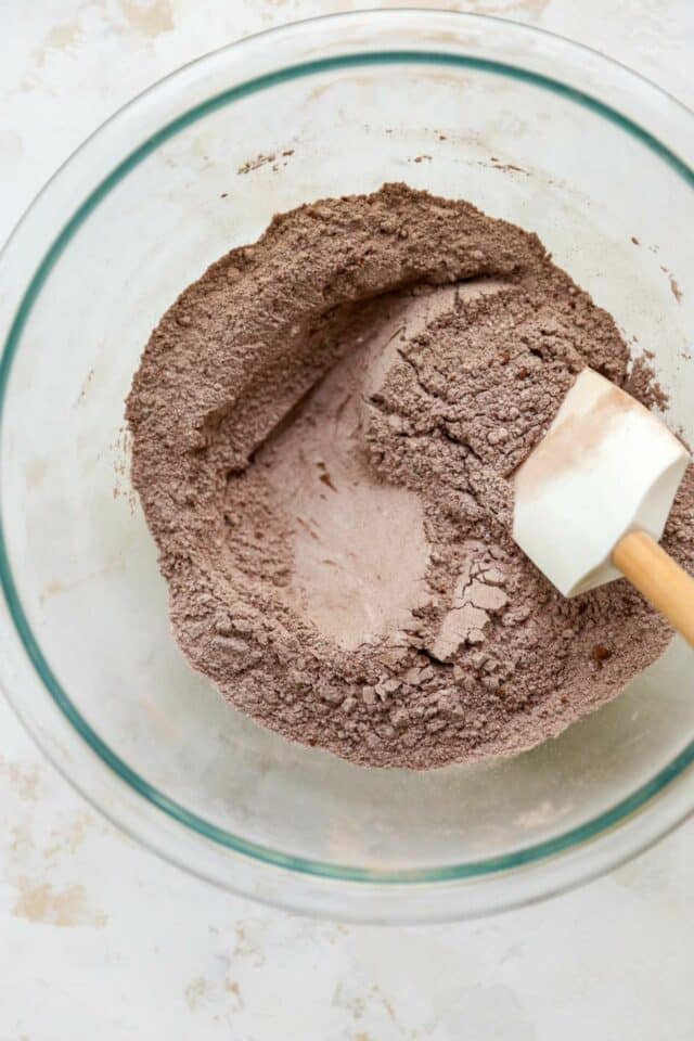 Stirring together flour with cocoa powder in a large bowl.