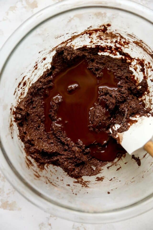 Stirring melted chocolate into chocolate donut batter.