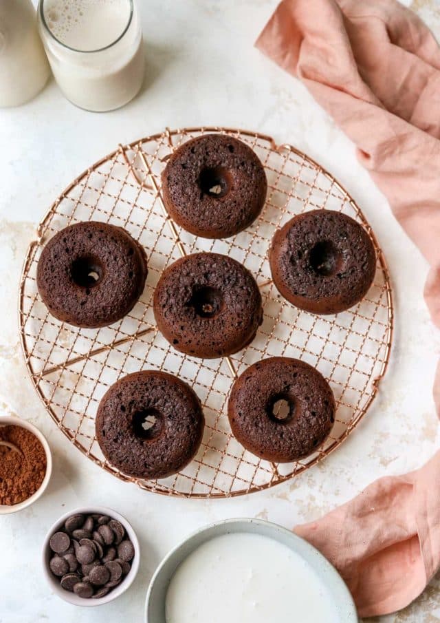 Chocolate donuts on a wire cooling rack.