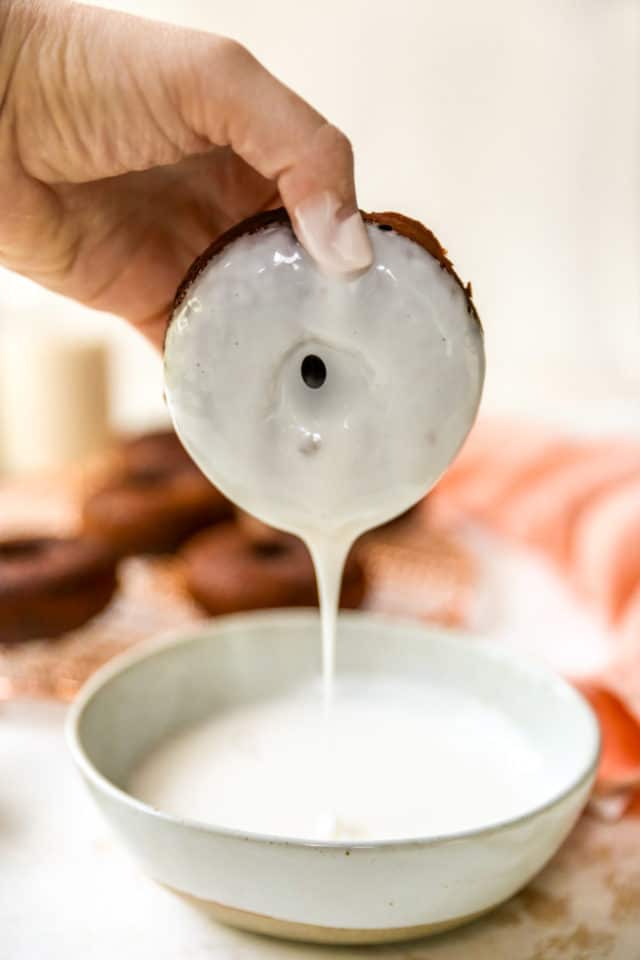 Dipping a chocolate donut into glaze.