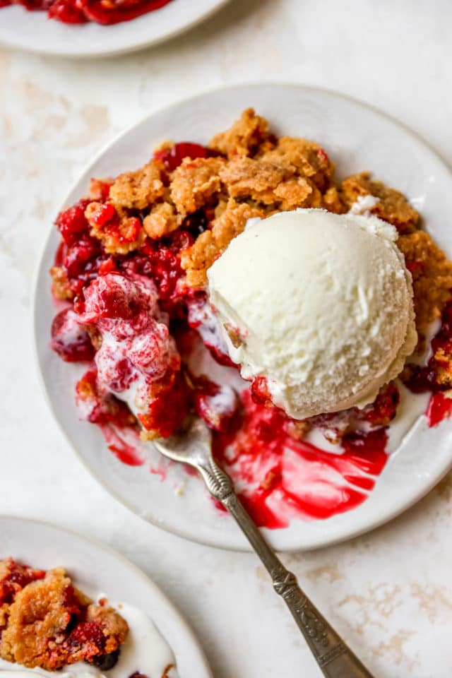 taking a fork of cherry dump cake with vanilla ice cream