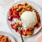 Serving of cherry dump cake topped with a scoop of vanilla ice cream.