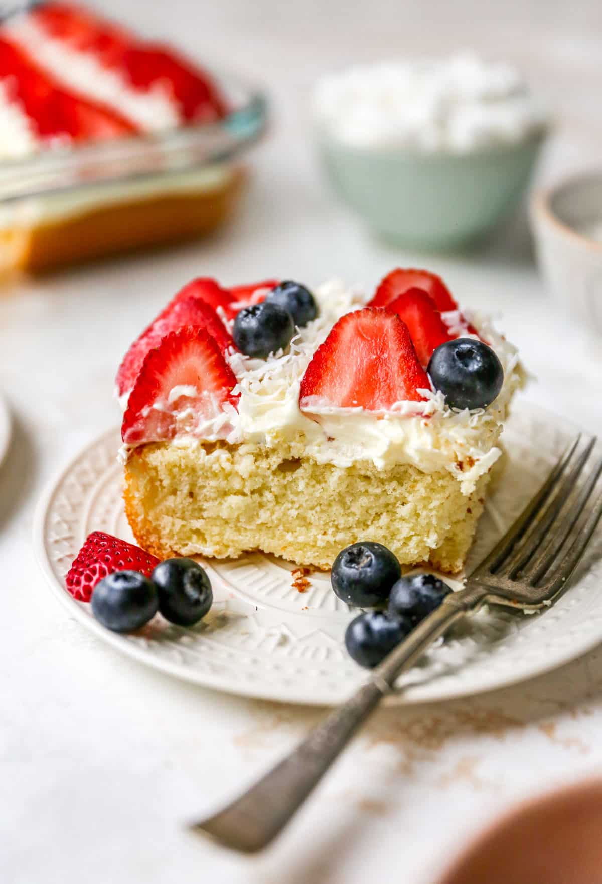 Slice of flag cake with whipped topping and strawberries.