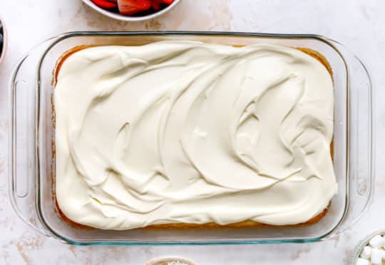 Whipped topping spread over yellow cake.