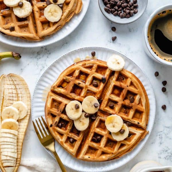 Banana waffles topped with banana, chocolate chips and syrup.