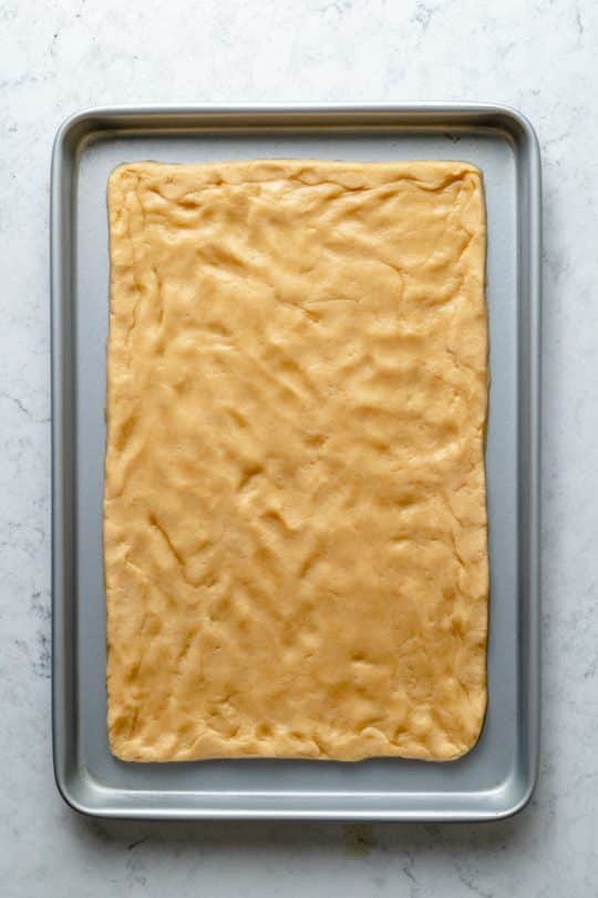 spreading sugar cookie dough out over a cookie sheet