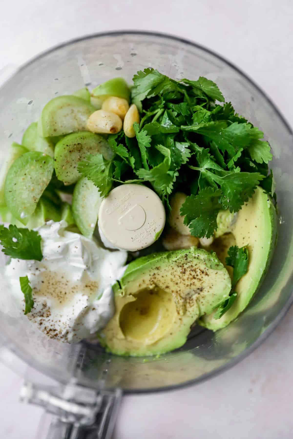 Avocado, cilantro, sour cream and tomatillos added to a food processor.