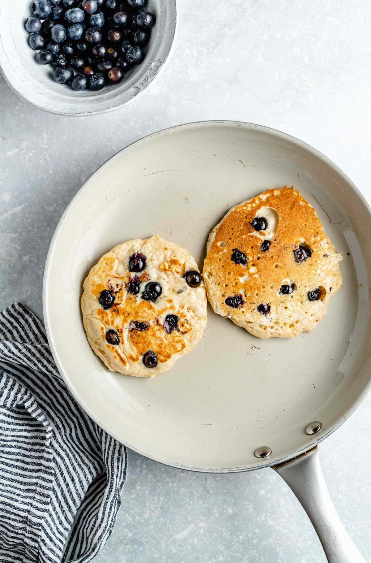 Golden brown blueberry pancakes cooking on a nonstick pan.