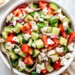 Cucumber tomato salad served with a serving spoon.