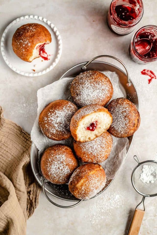 jelly donuts dusted with powdered sugar on a serving tray