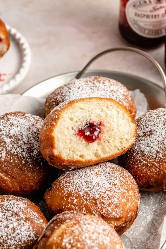 donut covered in powdered sugar and filled with raspberry jelly