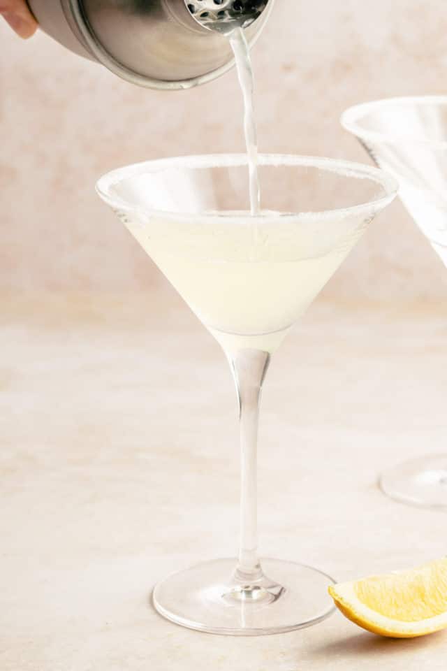 Pouring a lemon drop martini into a martini glass.