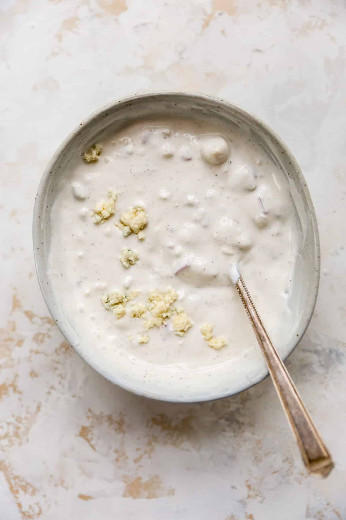 Homemade blue cheese dressing in a bowl with a spoon.
