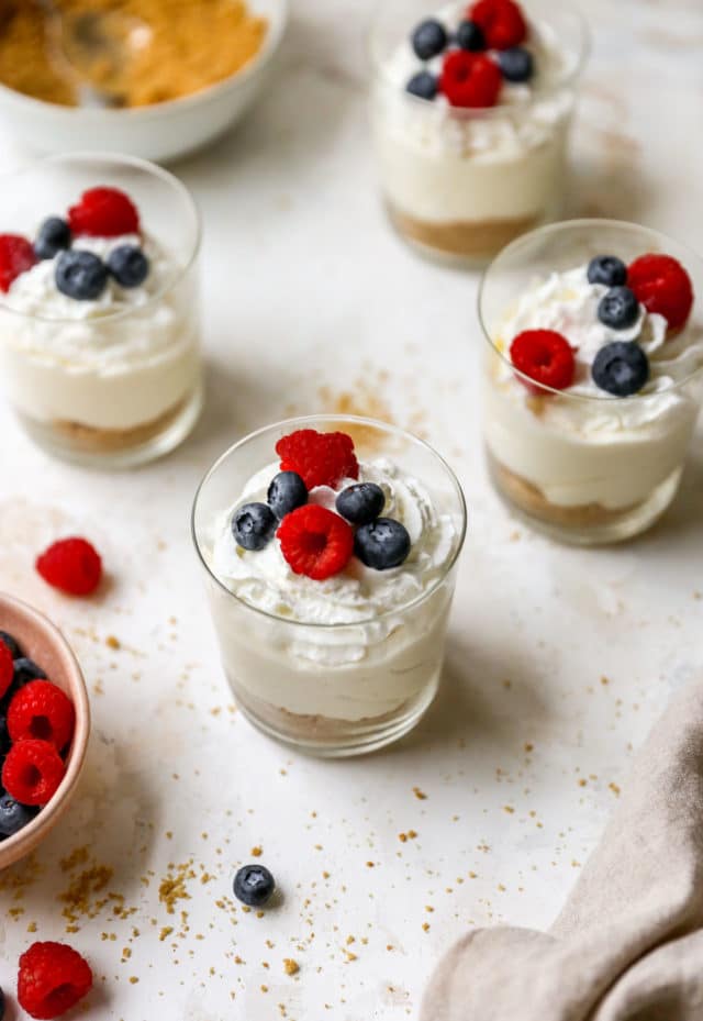 small glasses filled with a cheesecake filling and topped with fresh berries