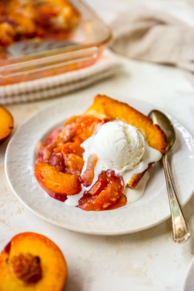 sliced peaches topped with melty ice cream and served with a spoon