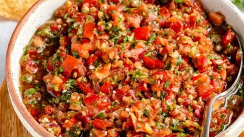 Homemade salsa served in a small white bowl with a spoon near chips.