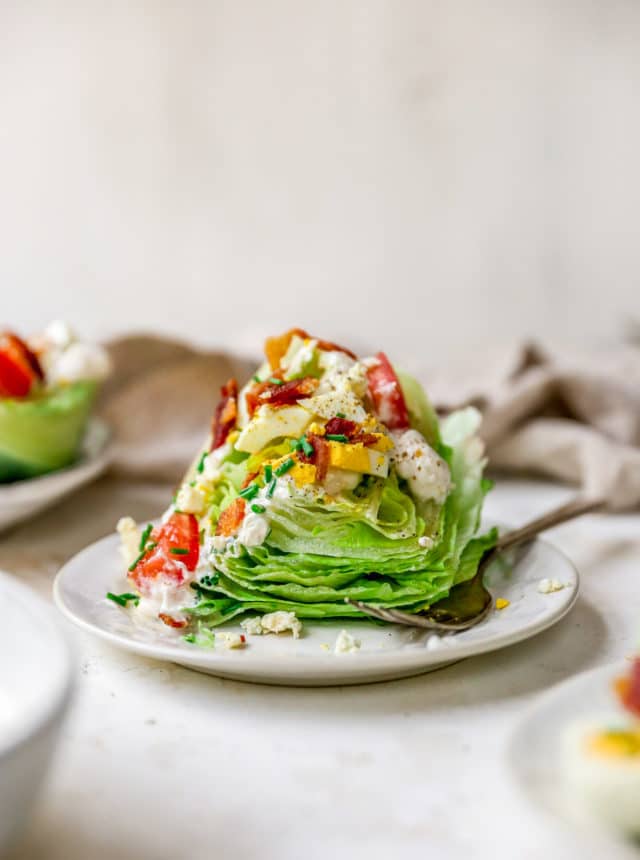 wedge of iceberg lettuce topped with blue cheese dressing, bacon and tomatoes