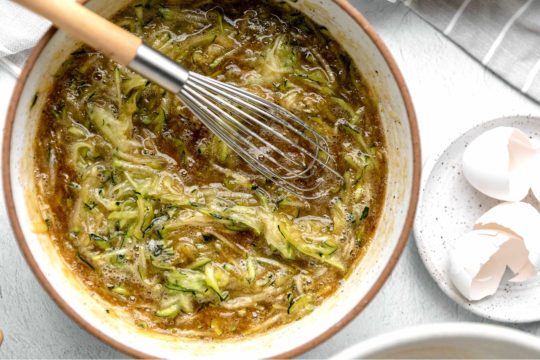 stirring shredded zucchini with wet ingredients