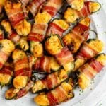 bacon wrapped jalapeno poppers on a large white serving tray
