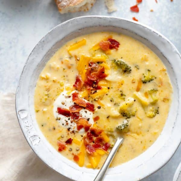 bowl of broccoli cheese soup topped with bacon, sour cream and shredded cheese