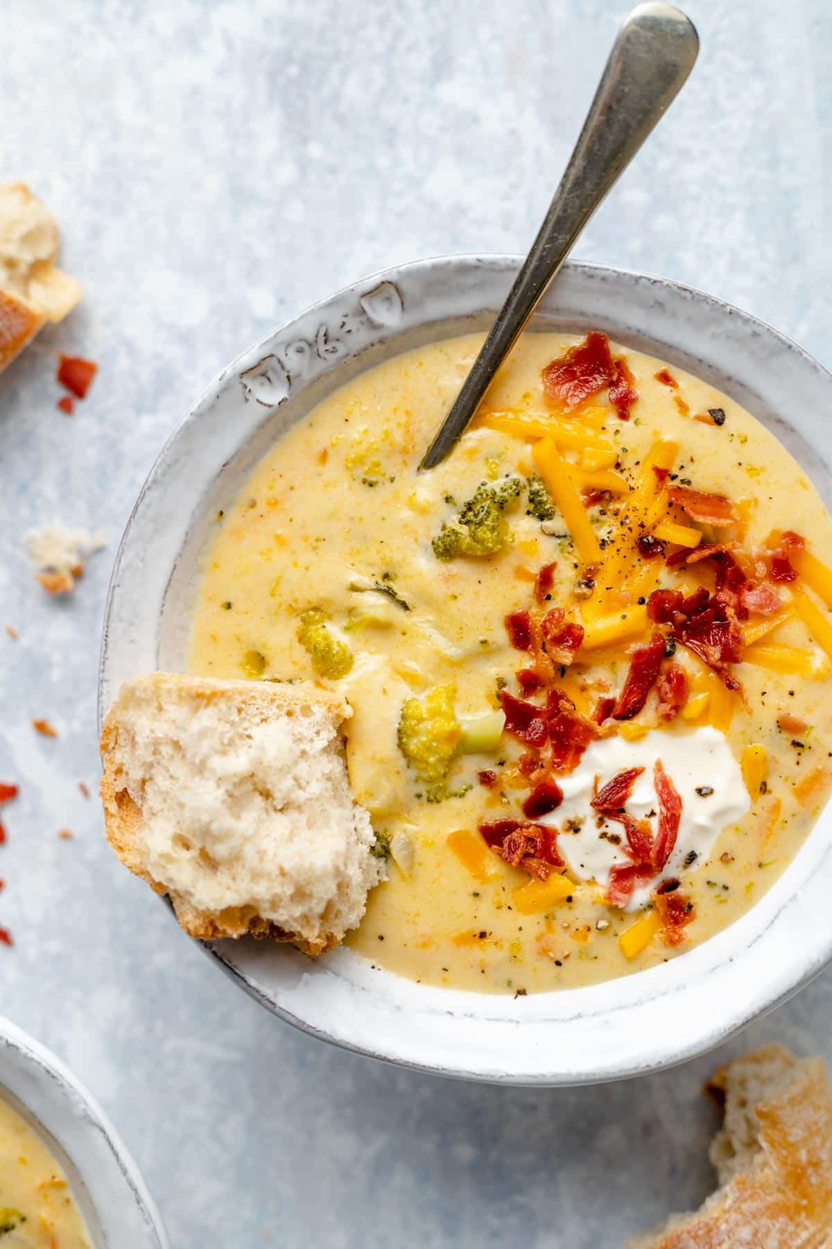 crusty bread dipped in a bowl of cheesy soup