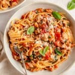 pasta with sausage served in a small white bowl with a fork