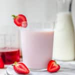 a glass of strawberry milk near fresh strawberries