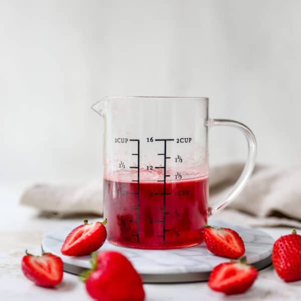 Strawberry simple syrup in a measuring glass.