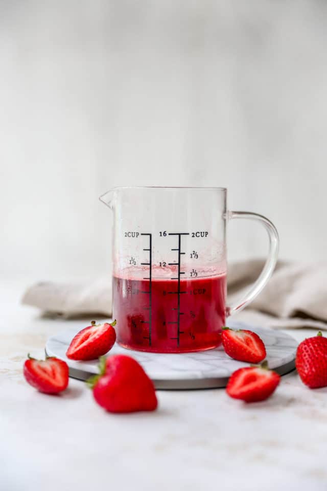 strawberry simple syrup in a measuring glass