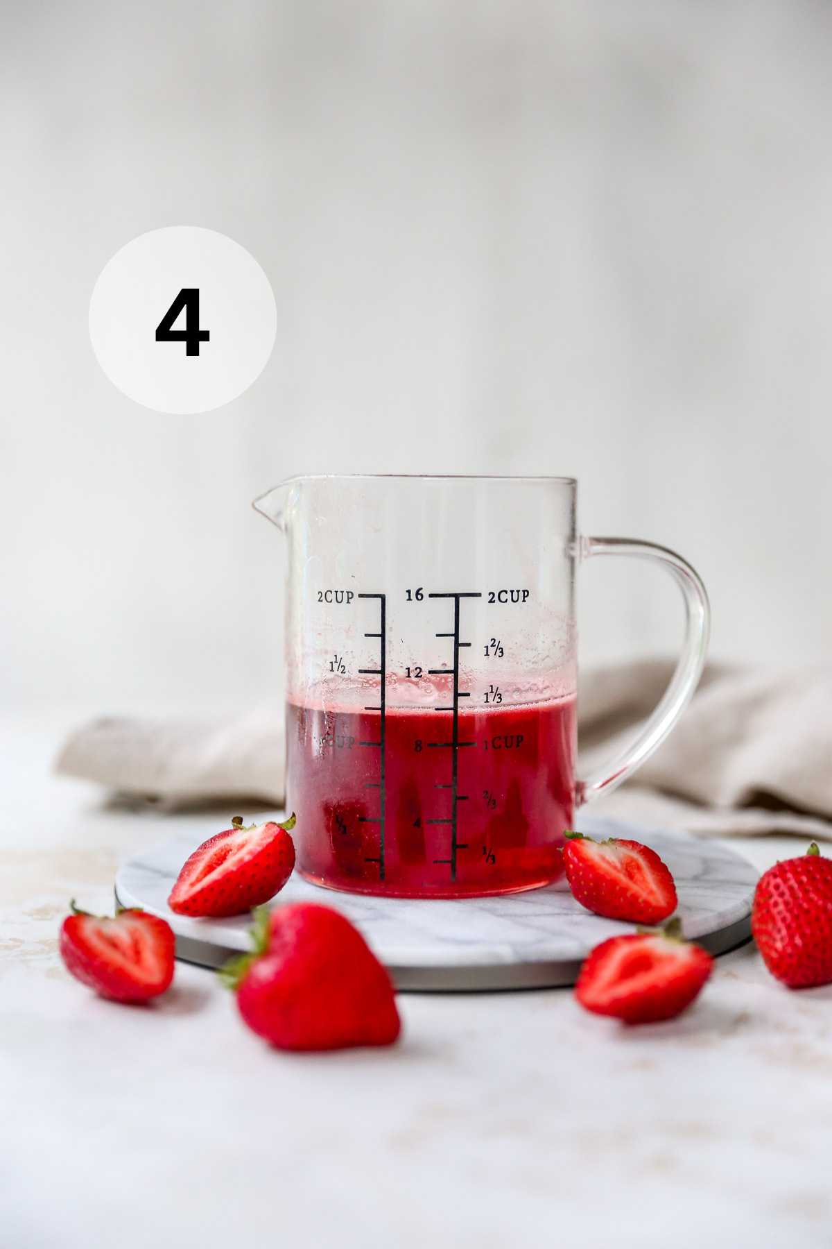 Strawberry simple syrup in a measuring glass.