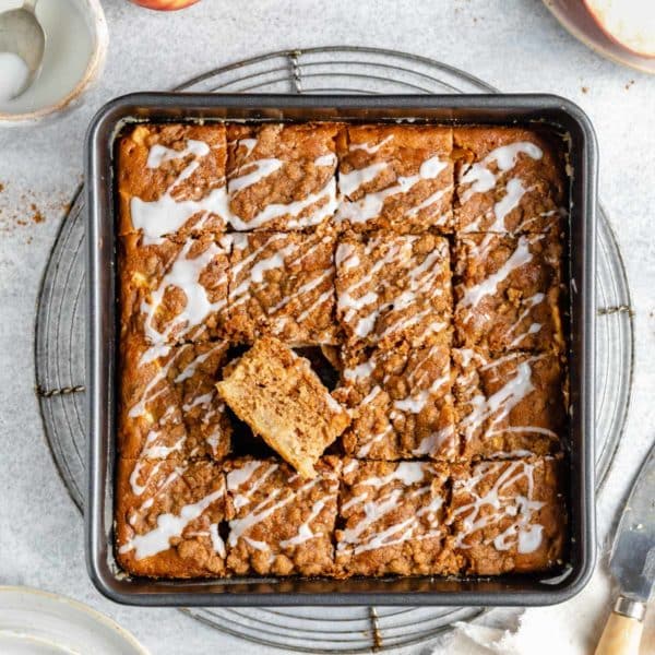 Apple coffee cake drizzled with glaze in a pan.