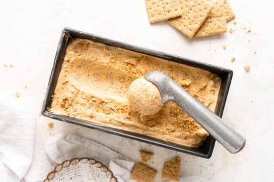 using an ice cream scoop to scoop pumpkin ice cream from a loaf pan