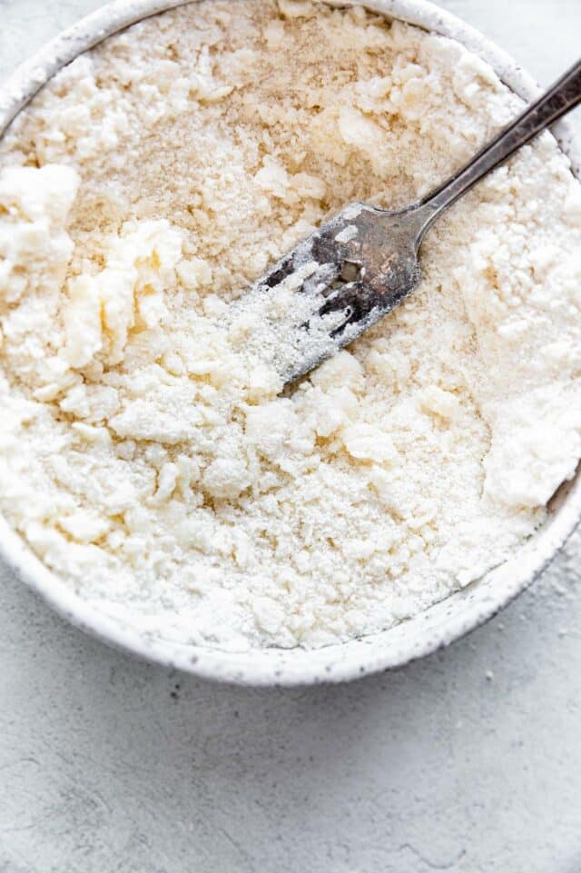 Using a fork to mix butter into flour.