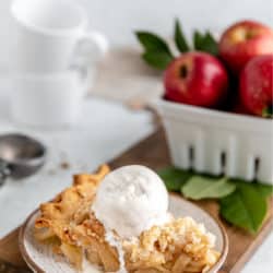 slice of apple crumb pie topped with a scoop of vanilla ice cream
