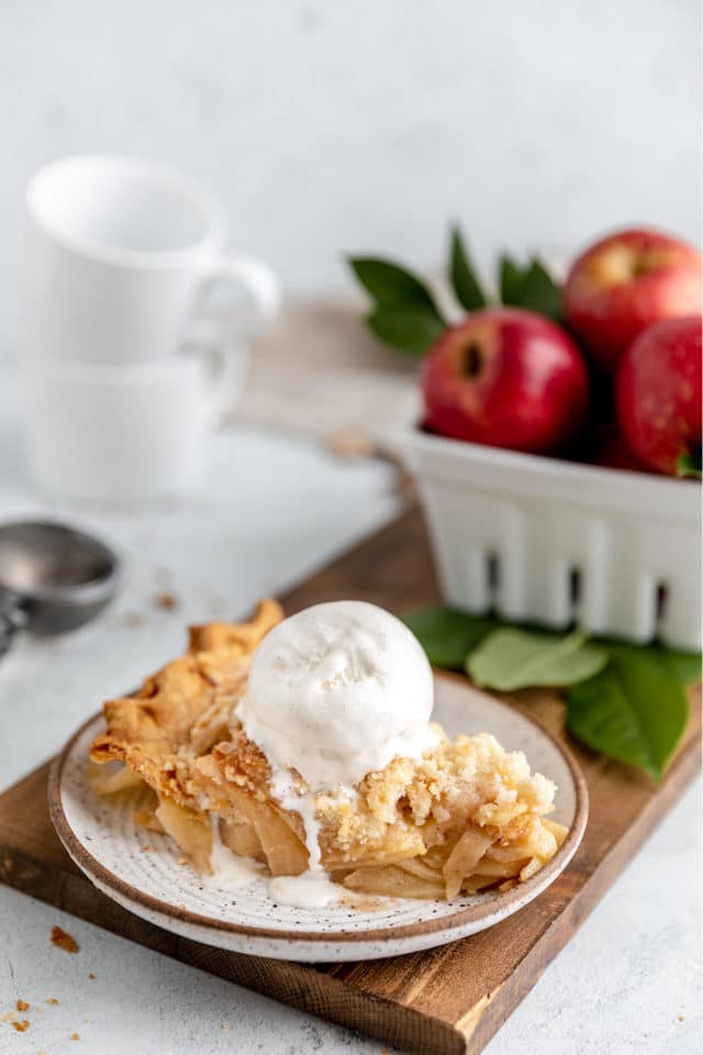 slice of apple crumb pie topped with a scoop of vanilla ice cream