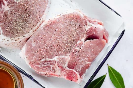 raw pork chops seasoned with salt and pepper