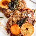Crock pot pork chops served with rice and garnished with orange slices.