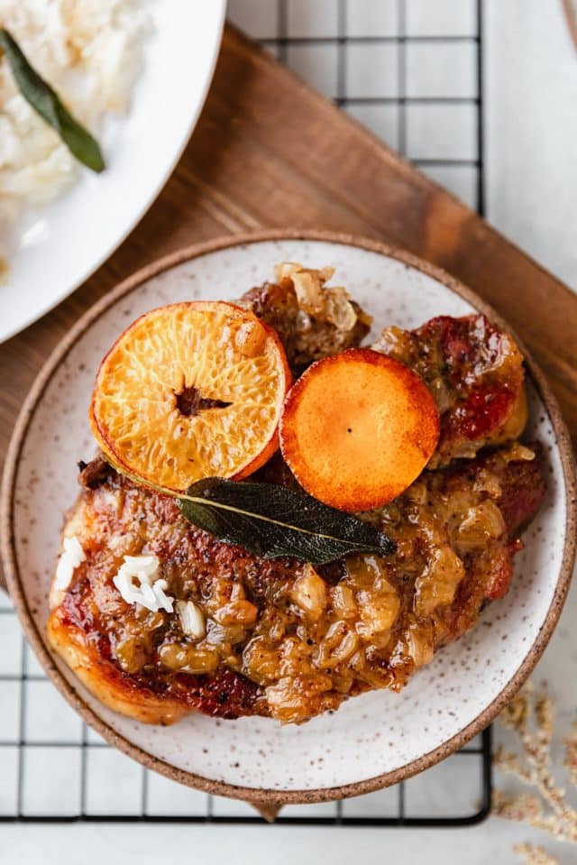 crock pot pork chops garnished with an orange slice and fresh sage