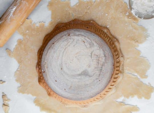 laying a pie dish over rolled pie crust dough