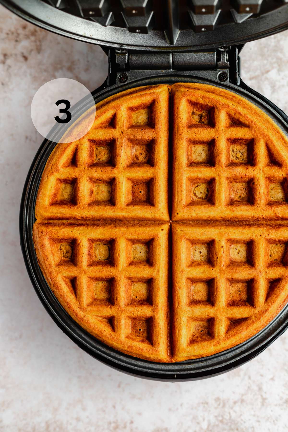 Cooked pumpkin waffle on a waffle maker.