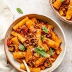 One pot pasta served in a white bowl garnished with basil.