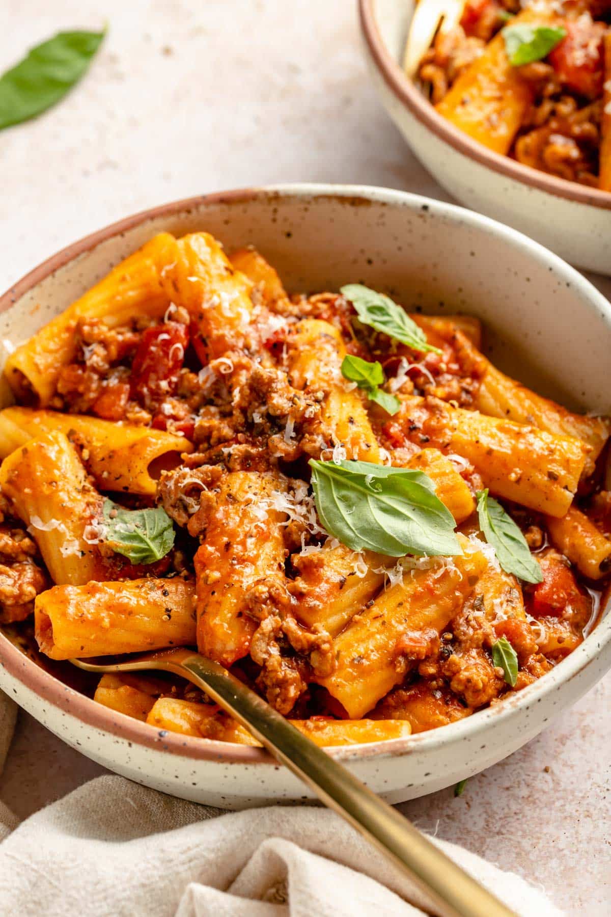 Pasta with meat sauce garnished with fresh basil.