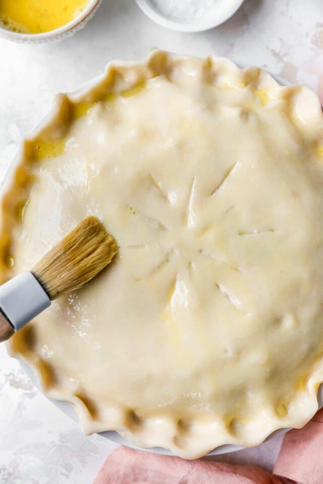 Brushing top crust of pot pie with egg wash.