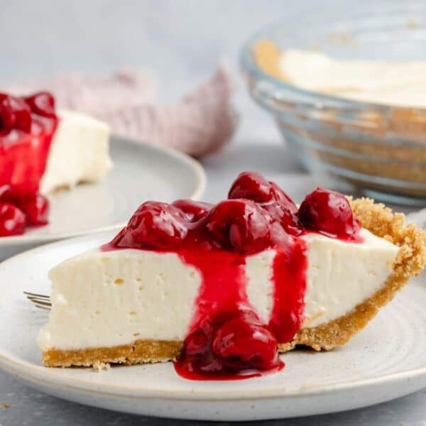 Slice of cream cheese pie topped with cherry pie filling.