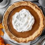 Pumpkin pie in a flaky crust and topped with whipped cream.