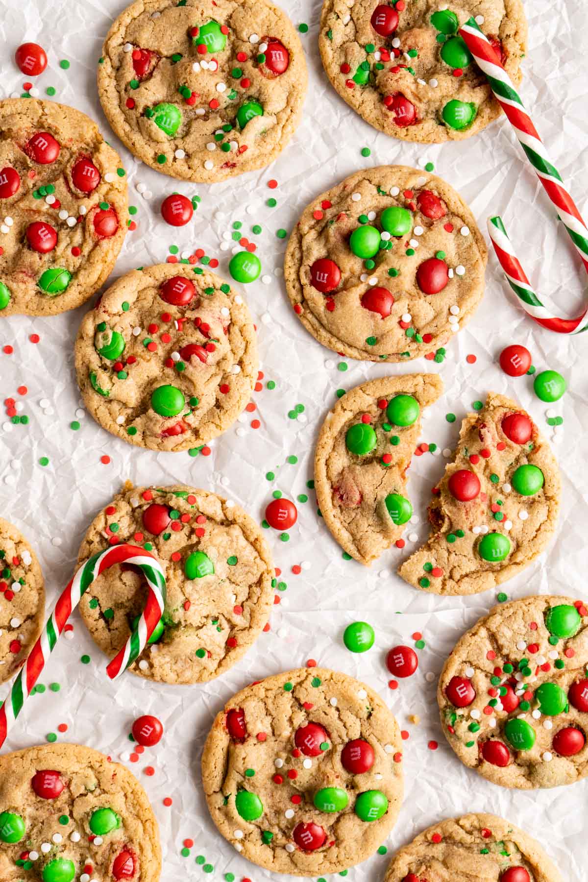 M&M Christmas cookies on parchment paper with candy canes.