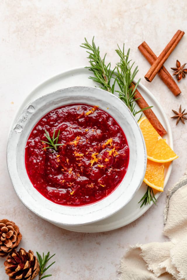 healthy cranberry sauce in a bowl with fresh rosemary and orange slices