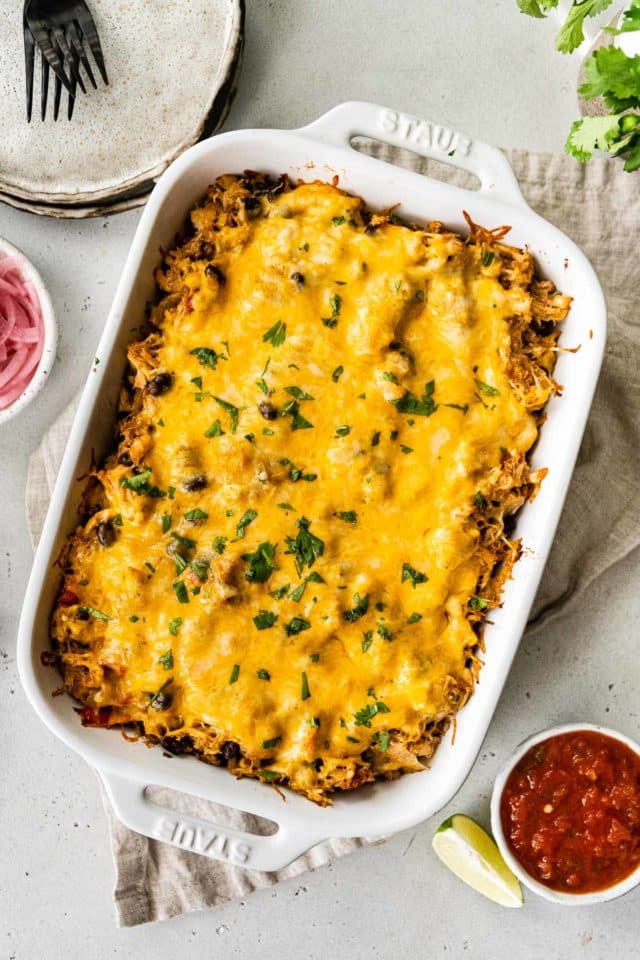 Mexican casserole topped with cheese in a white dish