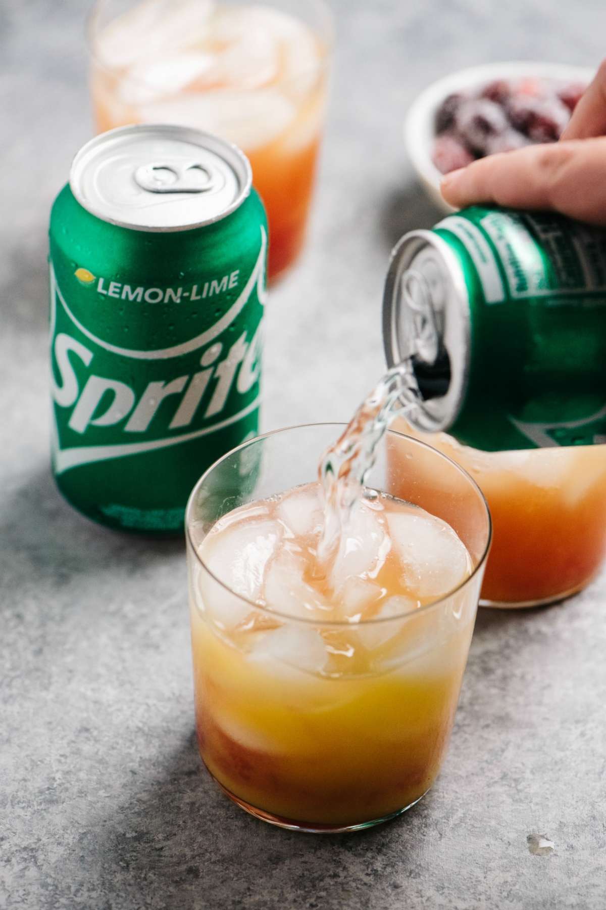 Pouring sprite into a cocktail made with cranberry juice, vodka and orange juice.