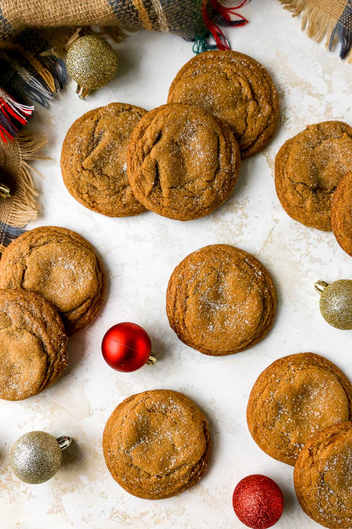Dark sugar cookies on a counter near Christmas ornaments.